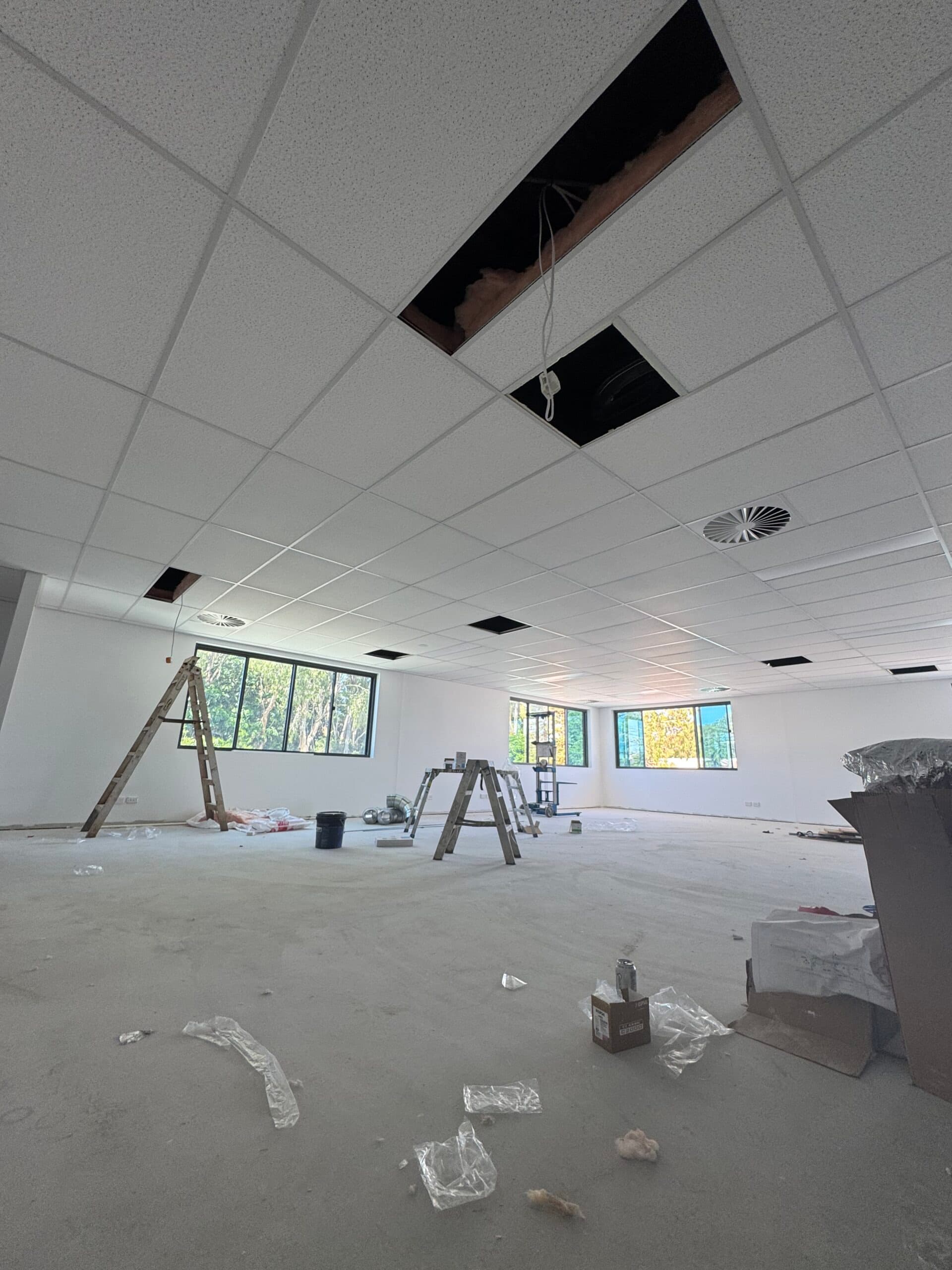 Suspended ceiling grid part-tiled during installation in a commercial office