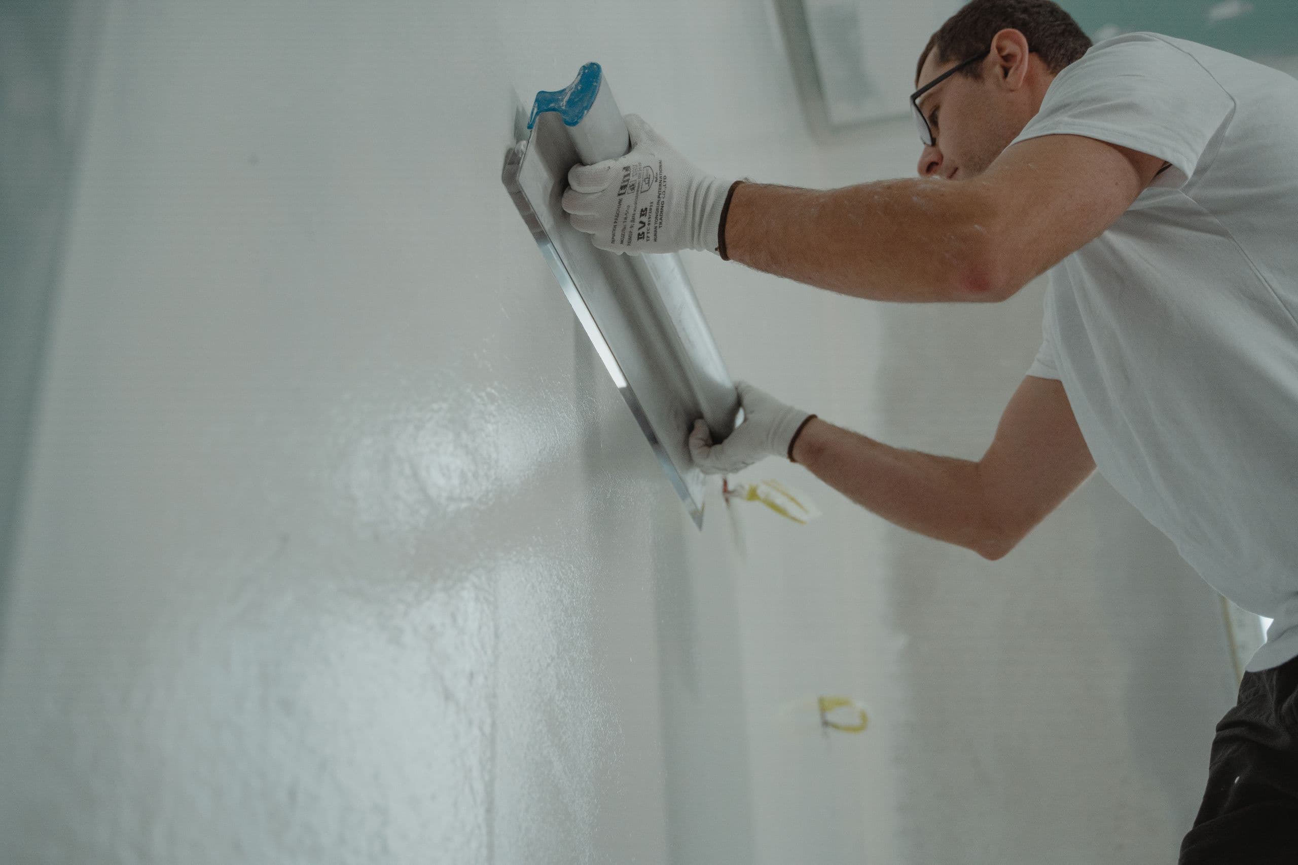 Plasterer smoothing jointing compound on a wall with a wide trowel