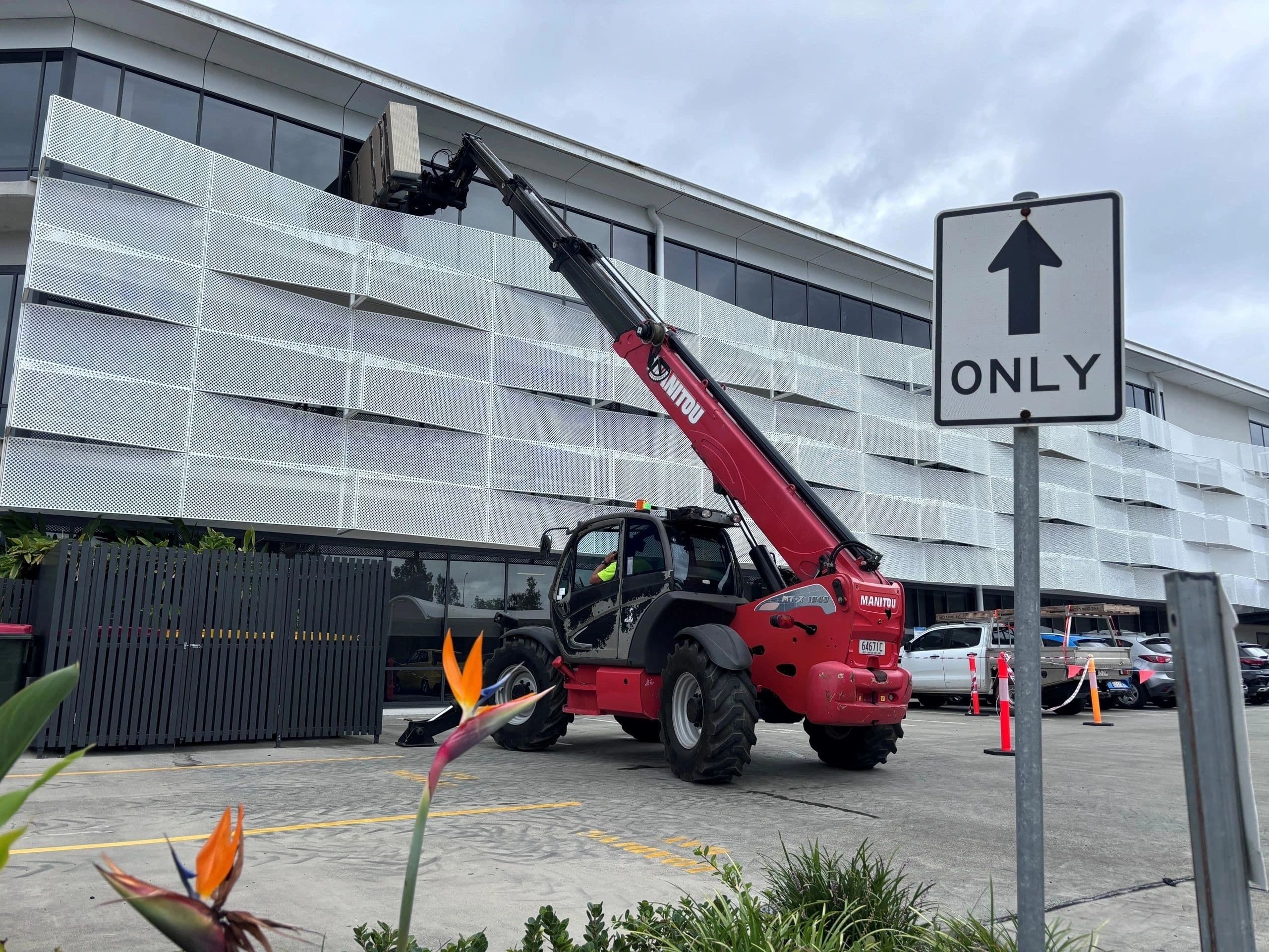 Telehandler lifting plasterboard sheets to an upper level of a commercial building